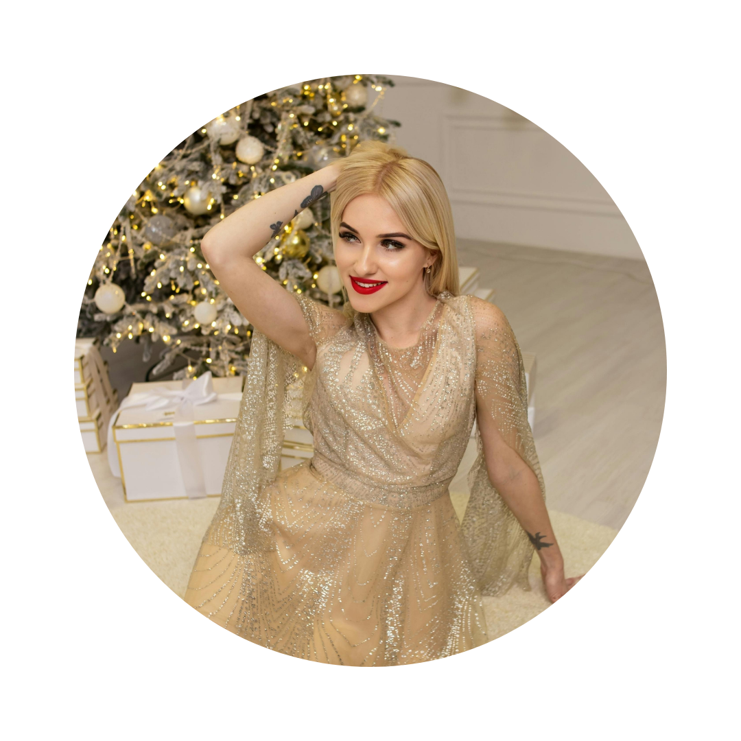 Woman in a gold dress posing in front of a decorated Christmas tree.